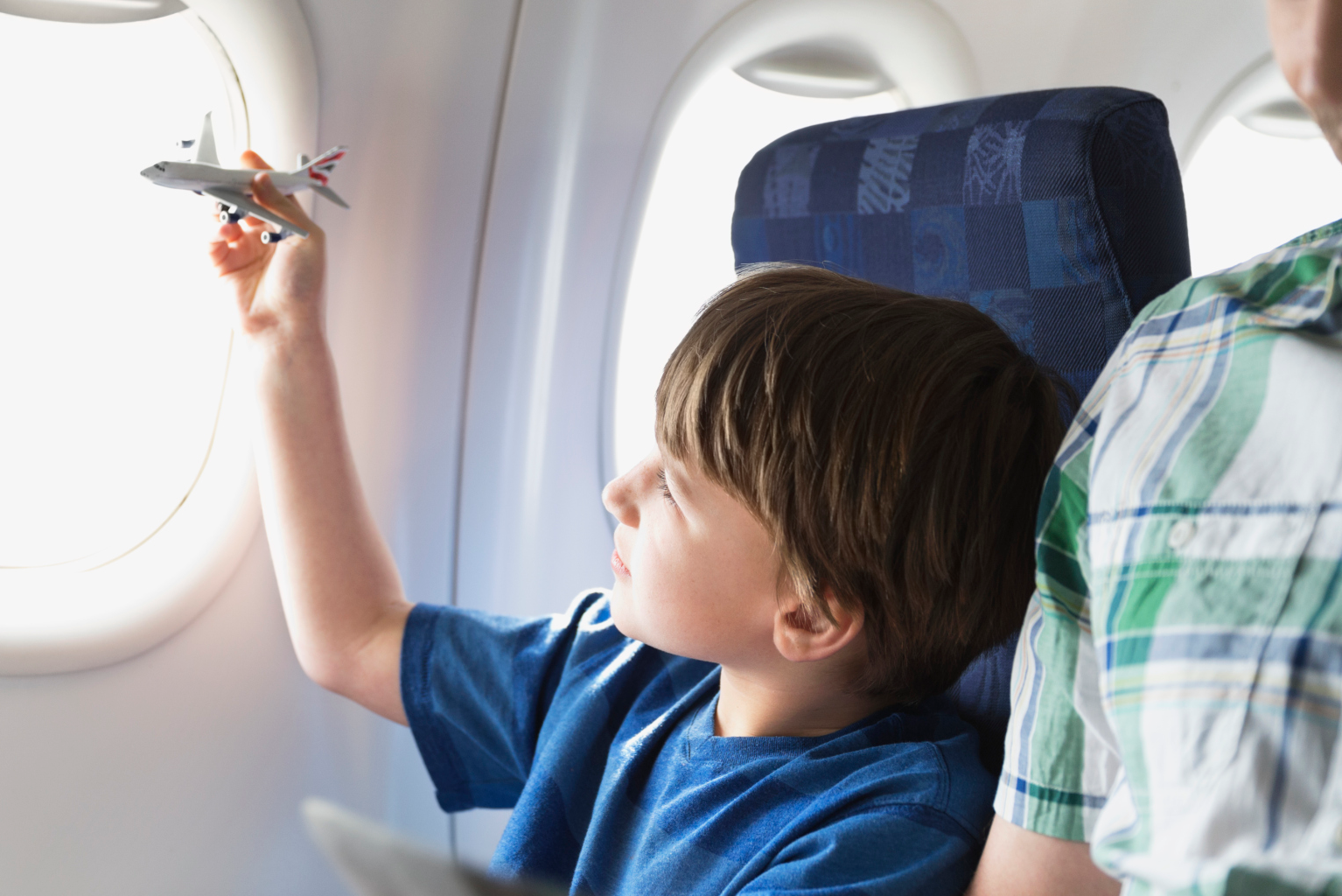 Boy on air plane playing with a toy air plane