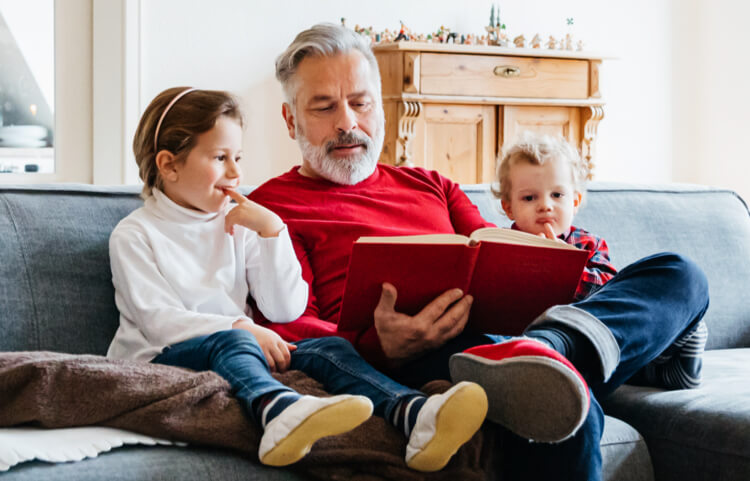 Elderly person reading to two younger people