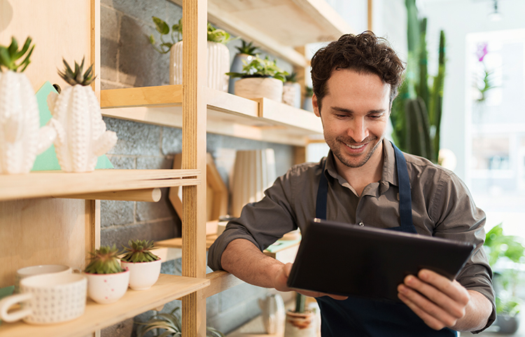 Small business owner looking and smiling at what they are reading on a tablet